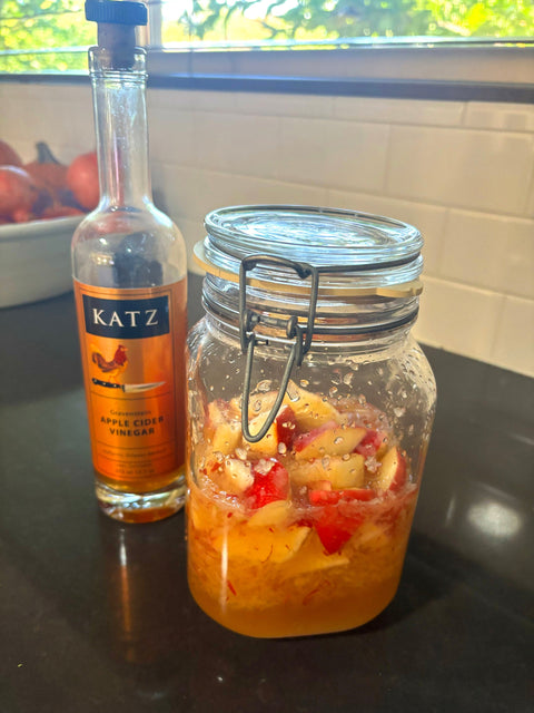 Photograph of KATZ  Farm Apple Shrub in a clear jar with a pop-top lid next to a bottle of KATZ Farm Gravenstein ACV