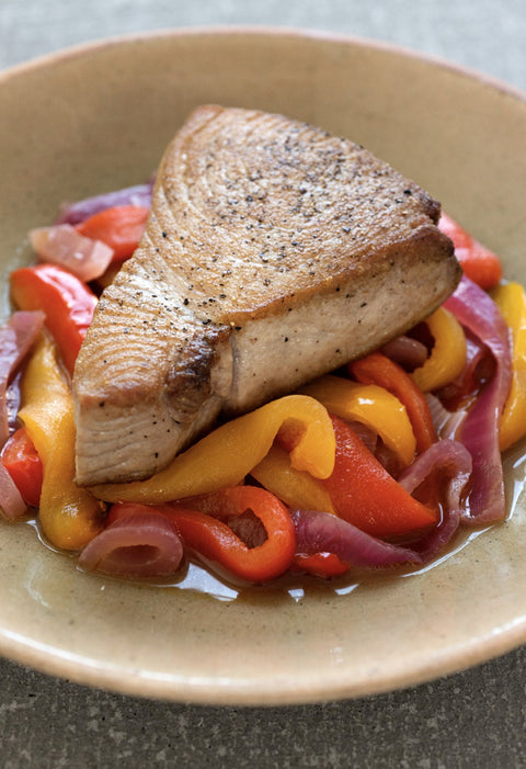 Seared tuna steak on a bed of sweet and sour peppers (red and yellow bell peppers and red onions in a clear sauce)